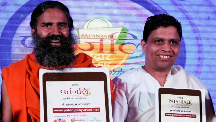 INDIA-ECONOMY-HEALTH Indian yoga guru Baba Ramdev (L) and Patanjali Ayurveda Managing Director, Acharya Balkrishna, pose for a photo during a press conference in New Delhi on January 16, 2018. India's hugely popular yoga guru on January 16 announced a tie-up of his Patanjali brand with a clutch of e-commerce majors including Amazon, eyeing a slice of the lucrative $1 billion online market for consumer goods. / AFP PHOTO / MONEY SHARMA (Photo credit should read MONEY SHARMA/AFP/Getty Images)